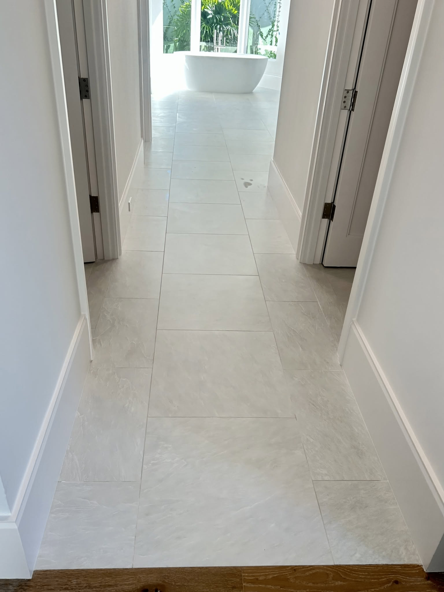 Large format light stone-look floor tile installation in hallway